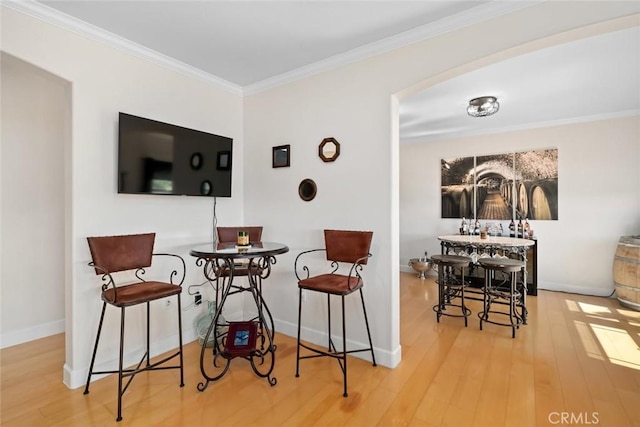 dining space with ornamental molding, baseboards, and wood finished floors