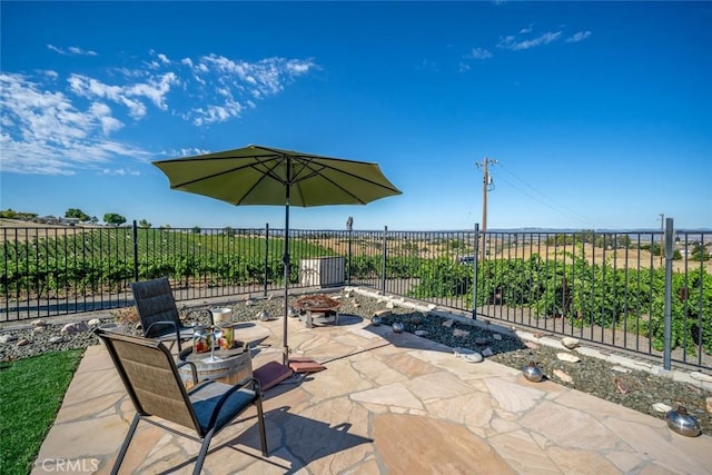 view of patio featuring an outdoor fire pit, fence, and a rural view