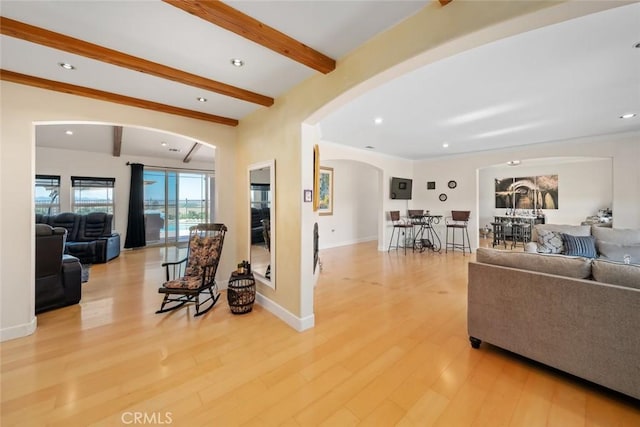 living area with light wood finished floors, baseboards, arched walkways, beamed ceiling, and recessed lighting