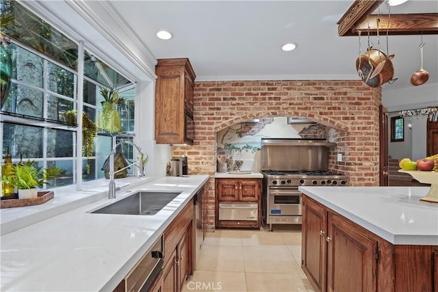 kitchen with sink, hanging light fixtures, light tile patterned floors, stainless steel appliances, and brick wall