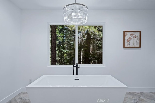 bathroom featuring a bathtub, a healthy amount of sunlight, and a chandelier