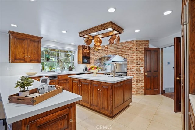 kitchen featuring light tile patterned floors, a kitchen island with sink, black microwave, and ornamental molding