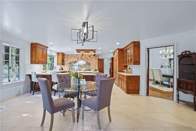 dining area with light tile patterned floors, ornamental molding, and an inviting chandelier