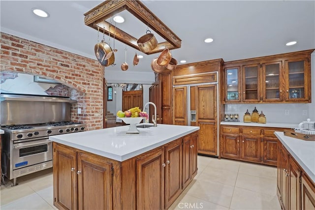 kitchen featuring sink, an island with sink, light tile patterned floors, and premium appliances