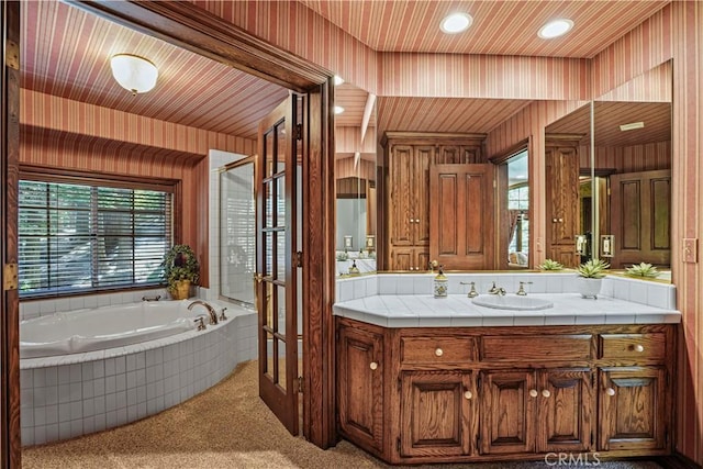 bathroom featuring vanity, a relaxing tiled tub, and a wealth of natural light