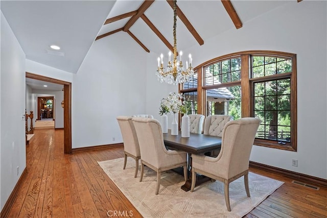 dining area with an inviting chandelier, beam ceiling, high vaulted ceiling, and light hardwood / wood-style flooring