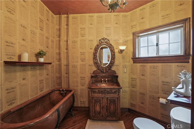 bathroom with a bathing tub, toilet, and hardwood / wood-style flooring