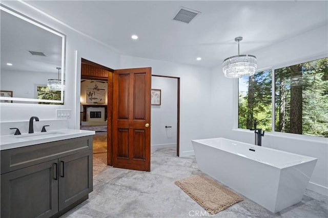 bathroom featuring a tub to relax in, vanity, and an inviting chandelier