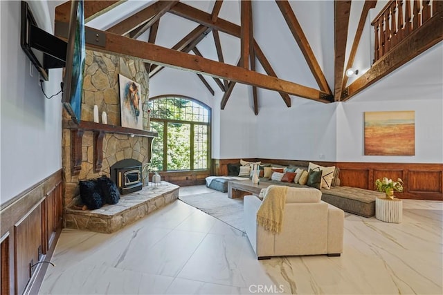 living room featuring a wood stove, wood walls, beamed ceiling, and high vaulted ceiling