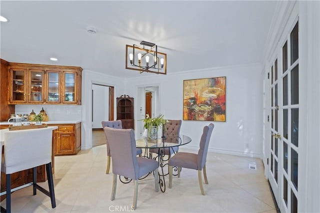 tiled dining space with a chandelier, french doors, and ornamental molding