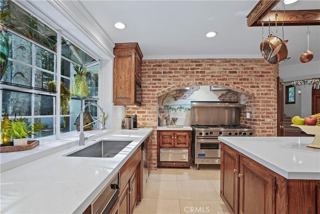 kitchen with sink, appliances with stainless steel finishes, decorative light fixtures, light tile patterned flooring, and brick wall