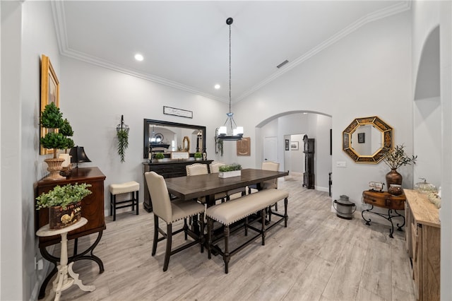 dining room featuring crown molding, lofted ceiling, light hardwood / wood-style flooring, and a chandelier