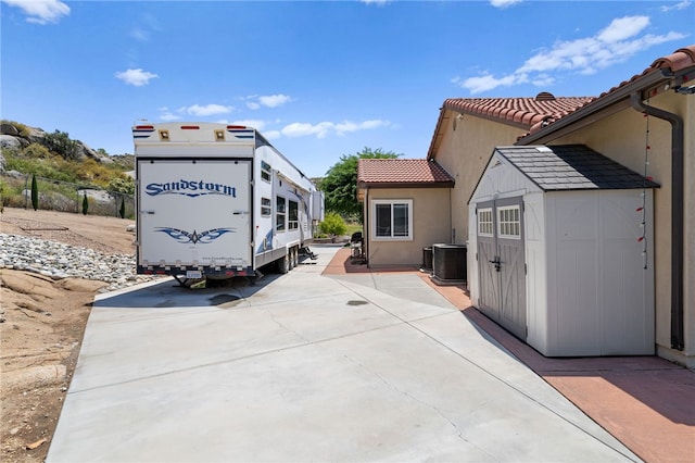 exterior space featuring a storage shed, central AC, and a patio area