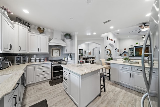 kitchen with stainless steel range, premium range hood, a center island, and white cabinetry