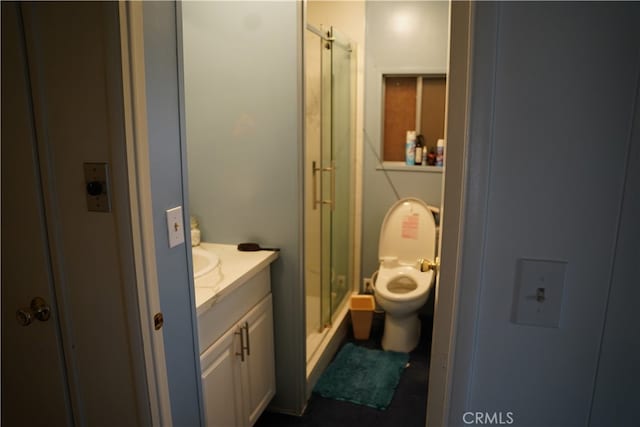 bathroom featuring vanity, a shower with shower door, and toilet