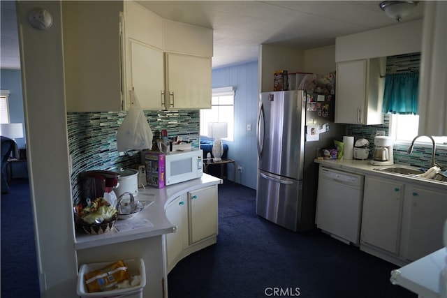 kitchen with white appliances, white cabinetry, sink, and tasteful backsplash