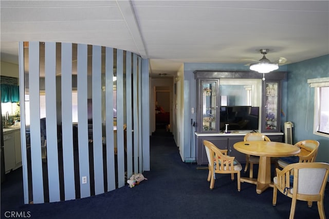 dining space with dark colored carpet and beamed ceiling