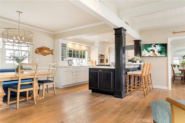 kitchen featuring light hardwood / wood-style flooring, beamed ceiling, a notable chandelier, oven, and white cabinets