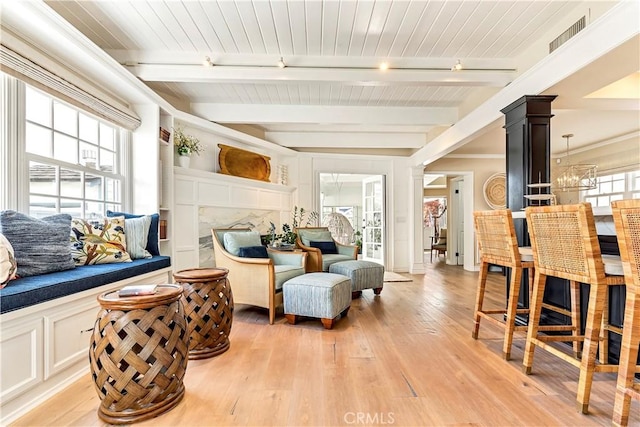 sitting room featuring a healthy amount of sunlight, beam ceiling, and light hardwood / wood-style flooring