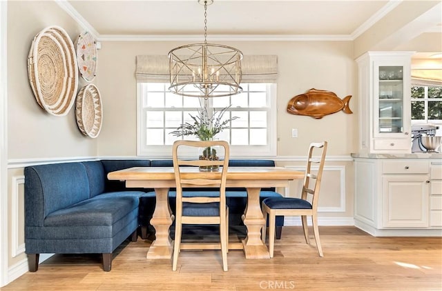 dining area with breakfast area, a notable chandelier, light wood-type flooring, and ornamental molding