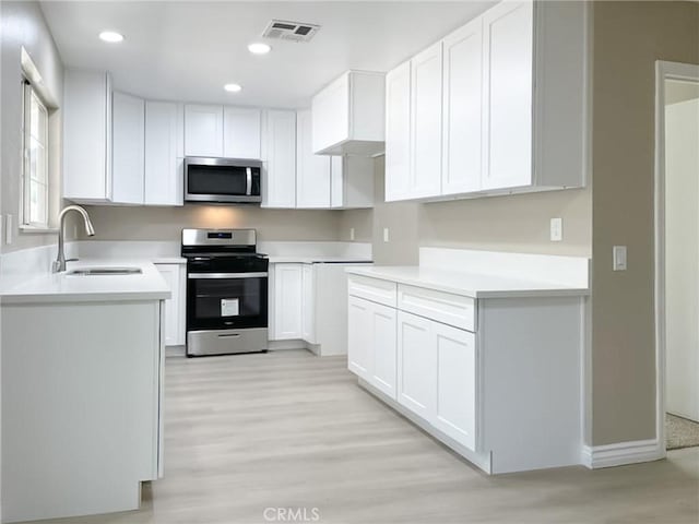 kitchen with stainless steel appliances, white cabinetry, and sink