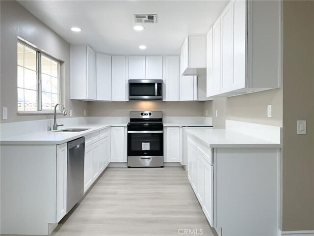 kitchen featuring sink, white cabinetry, appliances with stainless steel finishes, and light wood-type flooring