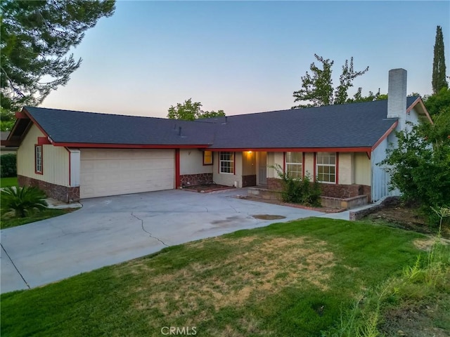 ranch-style house with a garage and a lawn