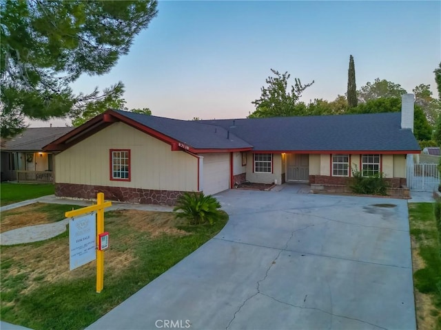 ranch-style home with a garage and a lawn