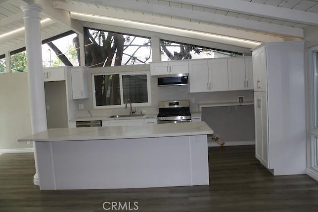 kitchen with white cabinets, vaulted ceiling with beams, stainless steel appliances, and sink