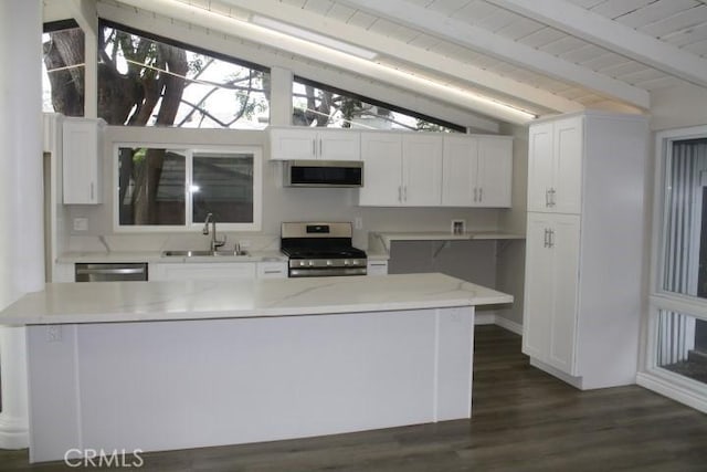 kitchen featuring sink, white cabinetry, stainless steel appliances, dark hardwood / wood-style floors, and lofted ceiling with beams