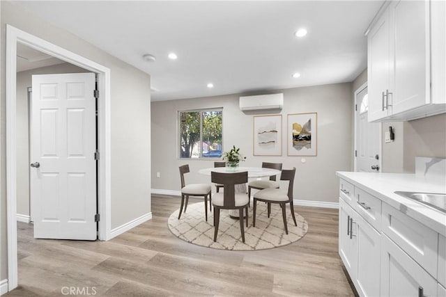 dining space featuring light wood-type flooring and a wall unit AC