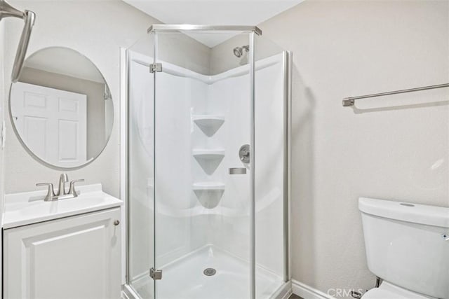 bathroom featuring vanity, toilet, and a shower with shower door