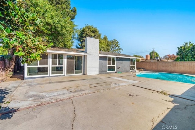 back of property with a fenced in pool and a patio area