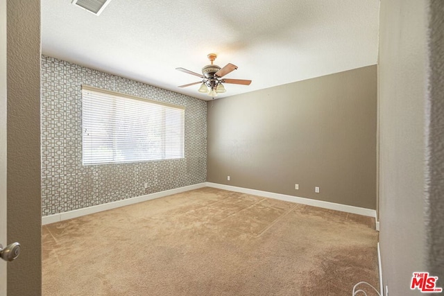 carpeted empty room featuring a textured ceiling and ceiling fan