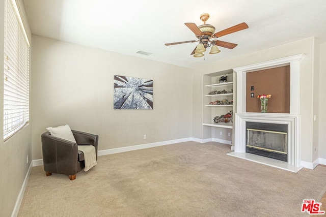 living area featuring built in features, light carpet, and ceiling fan