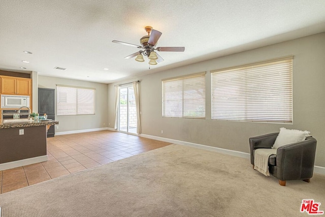 living room with light tile patterned flooring, a textured ceiling, and ceiling fan