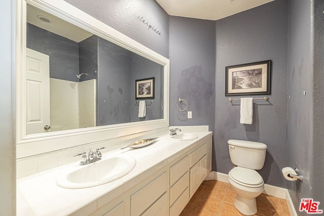 bathroom with tile patterned floors, vanity, toilet, and a shower