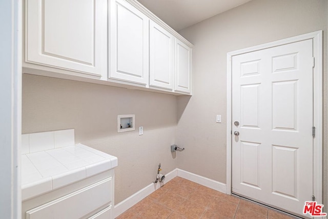 clothes washing area featuring washer hookup, gas dryer hookup, cabinets, and light tile patterned floors