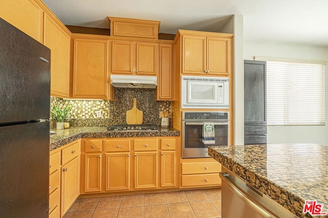 kitchen featuring tasteful backsplash, appliances with stainless steel finishes, light tile patterned floors, and a textured ceiling