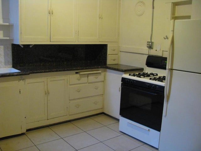 kitchen featuring backsplash, white appliances, light tile patterned flooring, and dark stone countertops