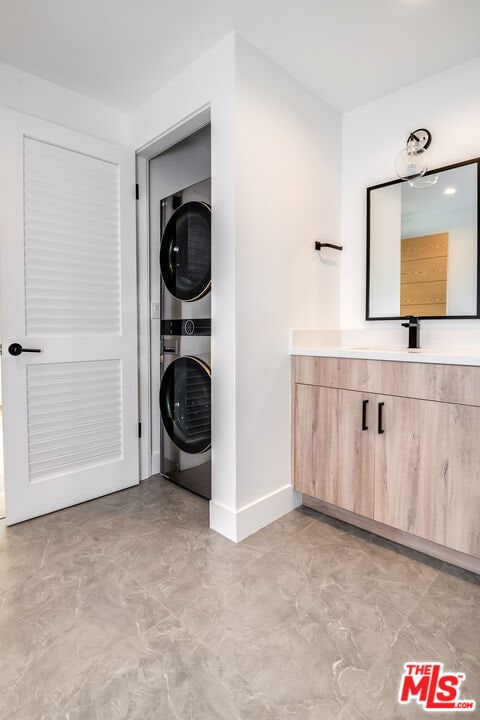 laundry room featuring stacked washer and clothes dryer and sink