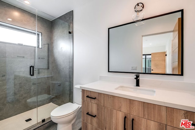 bathroom featuring vanity, a shower with shower door, and toilet