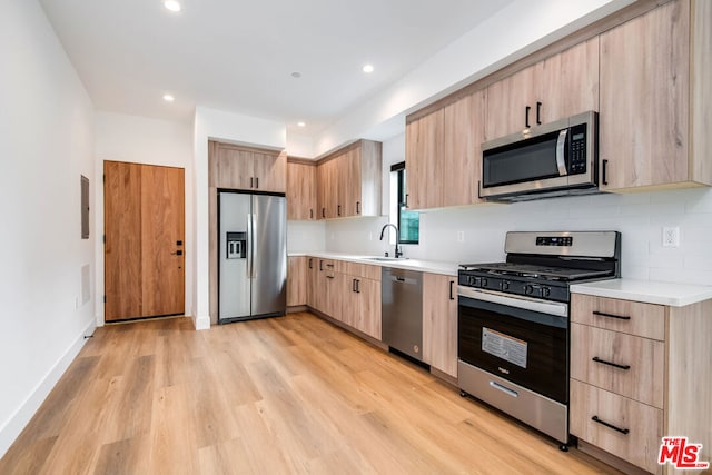 kitchen with sink, tasteful backsplash, light hardwood / wood-style flooring, light brown cabinets, and stainless steel appliances