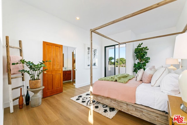 bedroom with ensuite bath and light hardwood / wood-style flooring