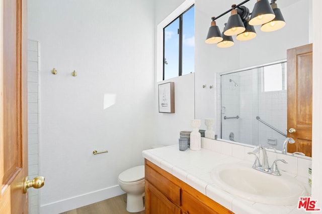 bathroom with toilet, an enclosed shower, vanity, a notable chandelier, and hardwood / wood-style flooring