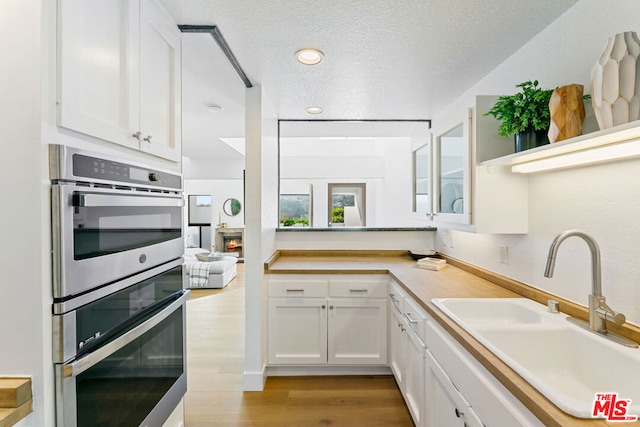 kitchen with white cabinetry, double oven, and sink