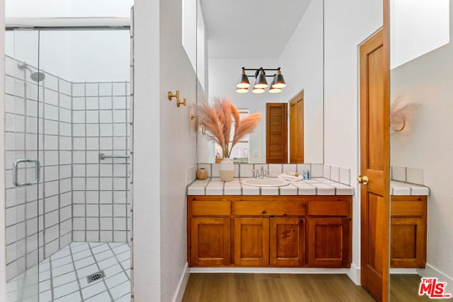 bathroom featuring walk in shower, vanity, and wood-type flooring