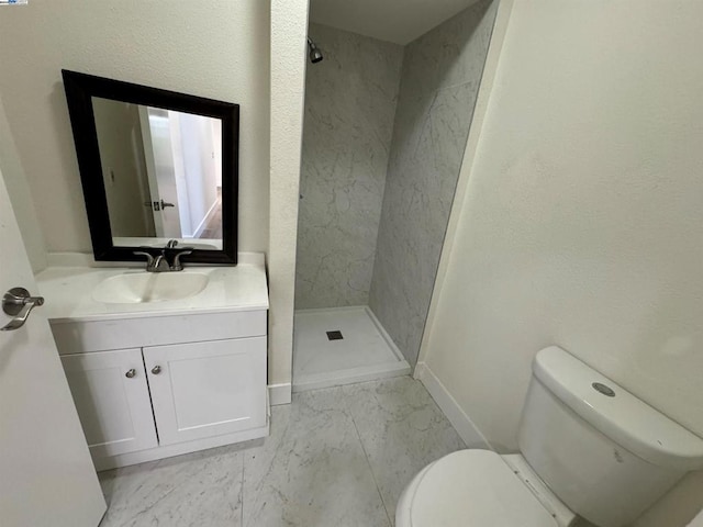 bathroom with vanity, toilet, and a tile shower