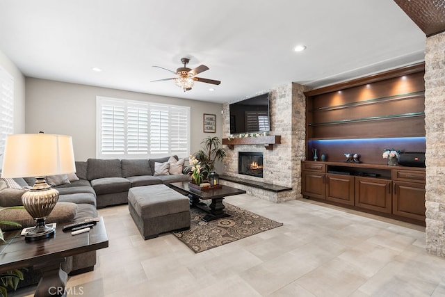 living room with a stone fireplace and ceiling fan