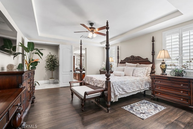 bedroom with ceiling fan, multiple windows, dark hardwood / wood-style floors, and a raised ceiling